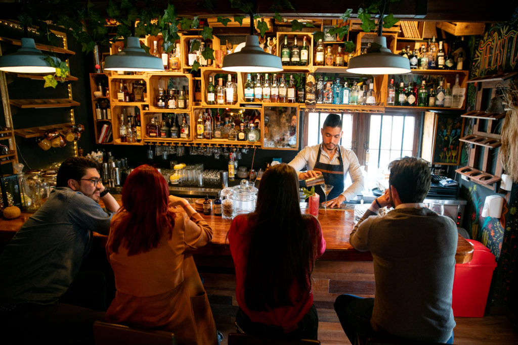 Latin American bartender at the bar making cocktails for people - food and drinks concepts